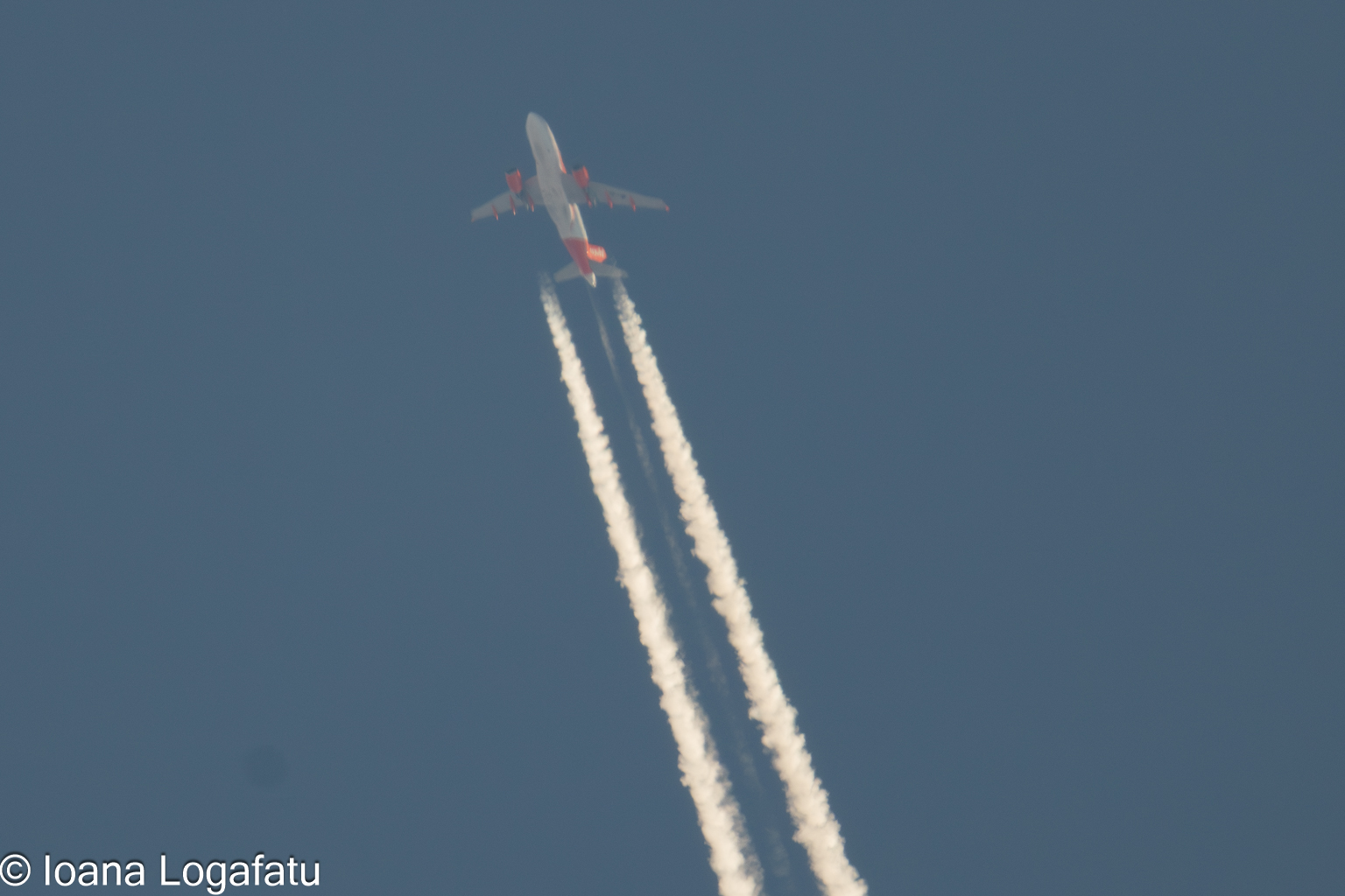 Plane soaring high above with soft vapor trails